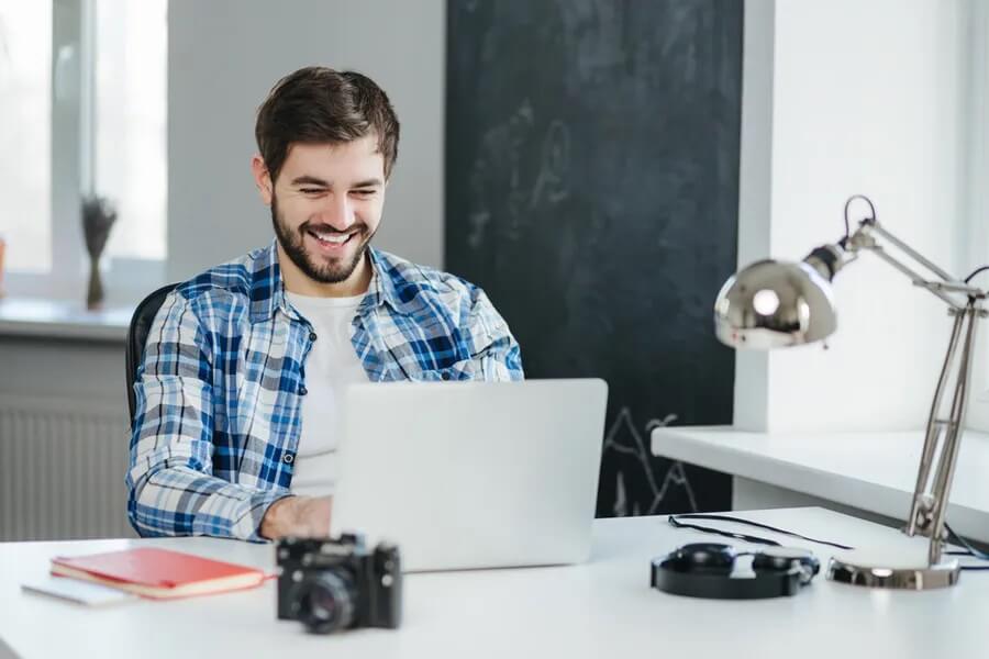 Man smiling while chatting on his laptop
